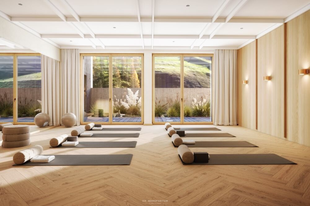 Ein heller Yogaraum mit Holzfußboden, ausgestattet mit Matten und Kissen, bietet eine ruhige Atmosphäre für Entspannung.