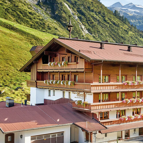 Das Hotel Alpenhof strahlt alpine Gemütlichkeit aus, umgeben von saftigem Grün und beeindruckenden Berggipfeln.