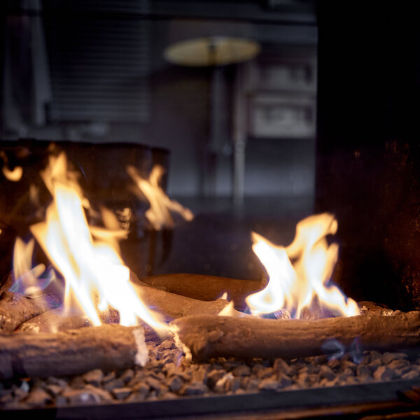 Flammen tanzen lebhaft über Holzscheite in einem modernen Kamin, während ein sanftes Licht den Raum erhellt.