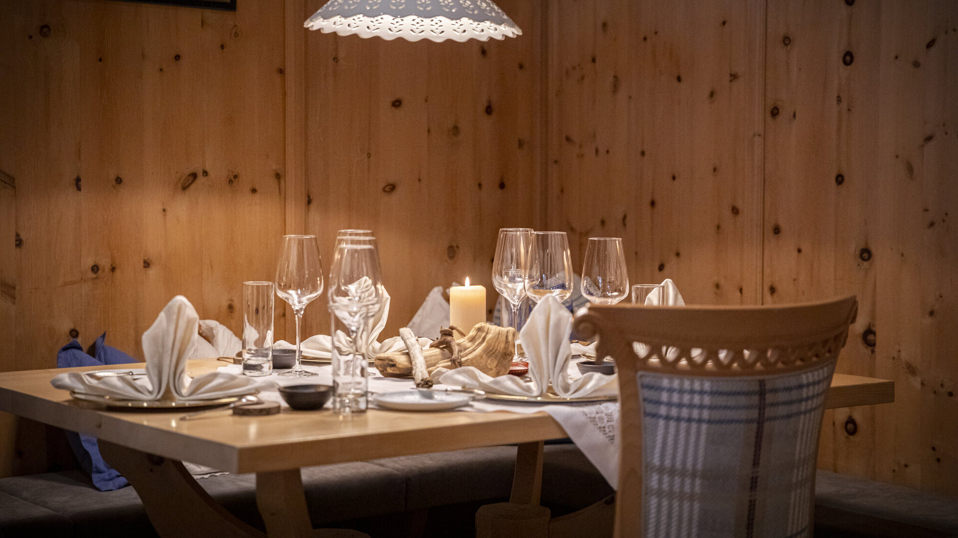 Ein elegant gedeckter Tisch in einem gemütlichen Restaurant mit Holzverkleidung und sanfter Beleuchtung durch eine Lampe.