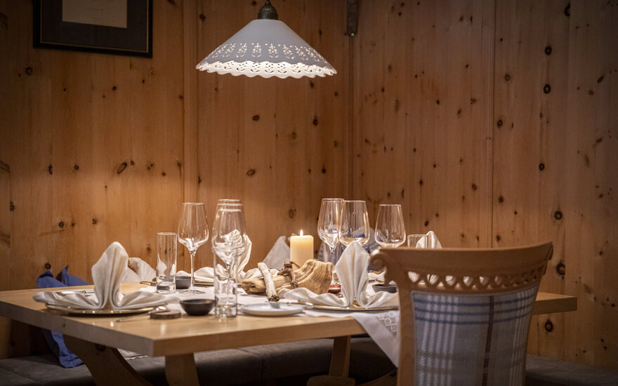 Ein elegant gedeckter Tisch in einem gemütlichen Restaurant mit Holzverkleidung und sanfter Beleuchtung durch eine Lampe.