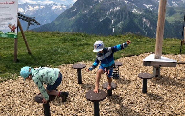 Die Kinder genießen einen sonnigen Tag im Freien, während sie auf einem Spielplatz mit verschiedenen Balanciergeräten spielen.