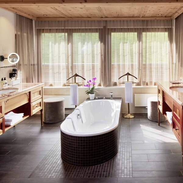 Ein elegantes Badezimmer mit einer freistehenden Badewanne, umgeben von Holz- und Steinoberflächen, die Gemütlichkeit ausstrahlen.