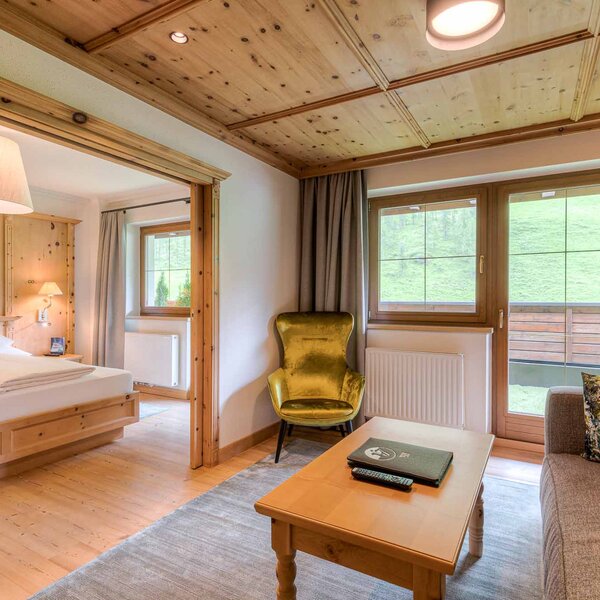 Ein gemütlicher Wohnraum mit Holzverkleidung, einem bequemen Sofa und einem goldenen Sessel, der zum Entspannen einlädt.