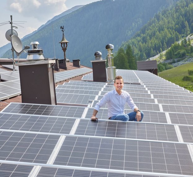 Mann auf Dach sitzend bei Solaranlage