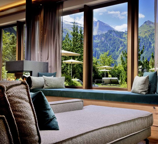 Liebe und brennendes Kaminfeuer vor großen Fenstern mit Blick in die Natur