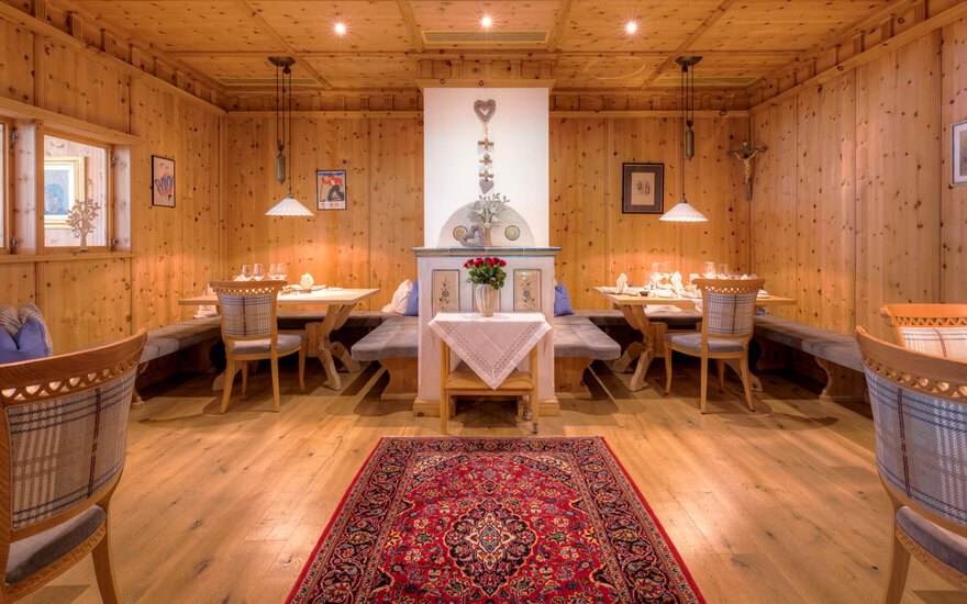 Ein gemütlicher Speisesaal mit Holzwänden, eleganten Tischen und einer schönen roten Teppichdekoration in der Mitte.