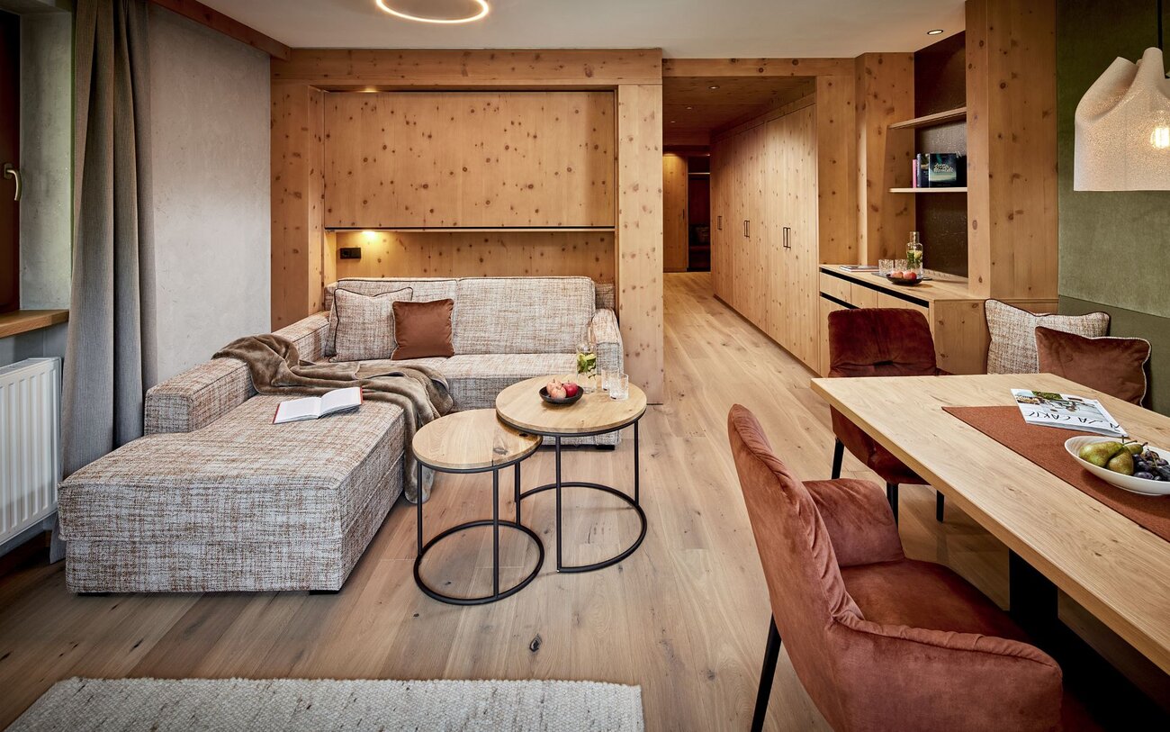 Ein gemütliches Wohnzimmer mit einer beigen Couch, einem kleinen Tisch und warmen Holzelementen, die eine einladende Atmosphäre schaffen.