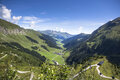 Ein atemberaubender Blick auf das grüne Tal, umgeben von majestätischen Bergen und einem strahlend blauen Himmel.