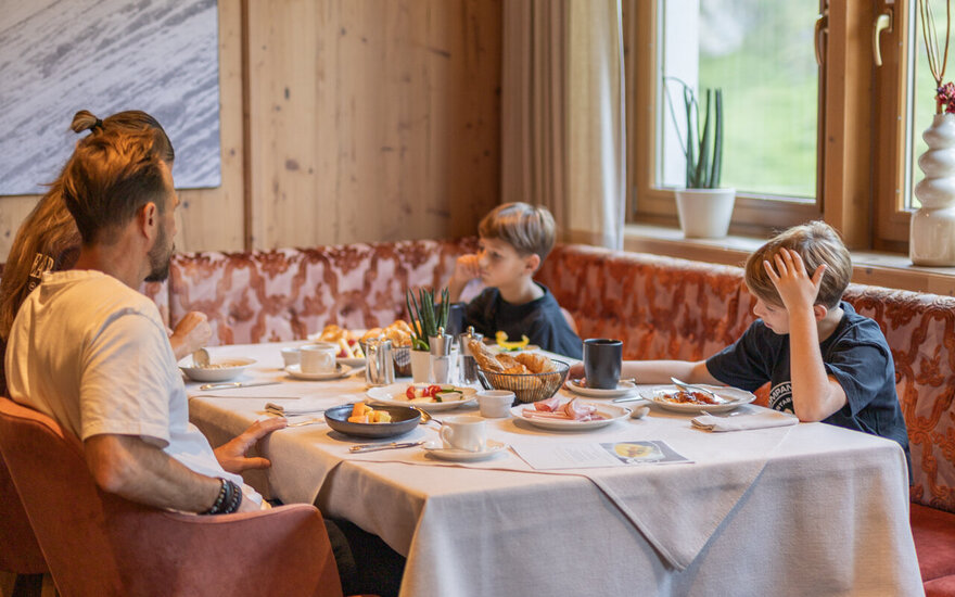 Eine Familie sitzt zusammen an einem gedeckten Frühstückstisch.