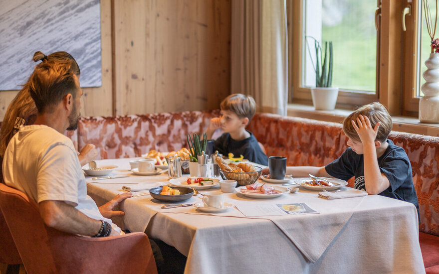 Eine Familie sitzt zusammen an einem gedeckten Frühstückstisch.