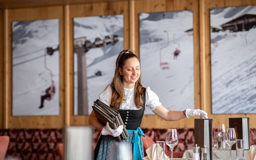 Mit einem freundlichen Lächeln stellt die Kellnerin die Weinkarten auf einen Tisch in einem Bergrestaurant auf.