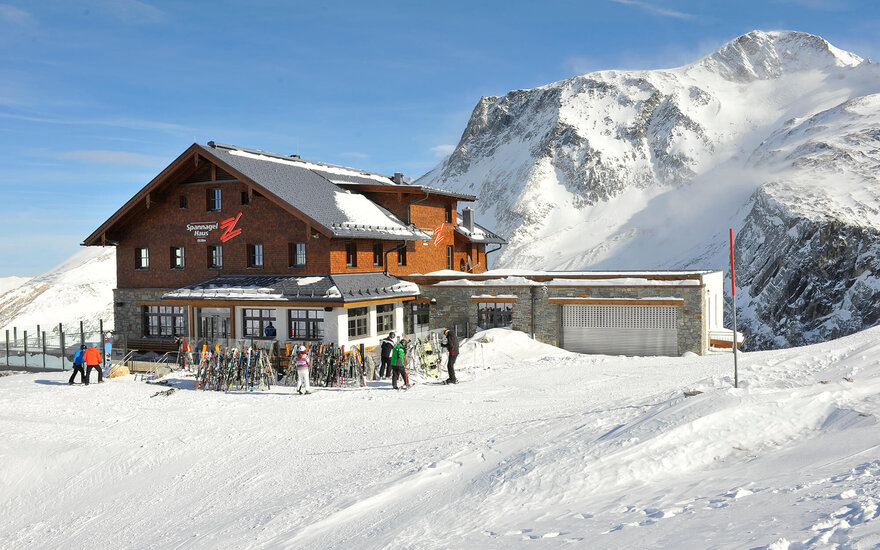 Das Spannagelhaus steht majestätisch in einer schneebedeckten Berglandschaft, umgeben von hohen Gipfeln und klarem Himmel.