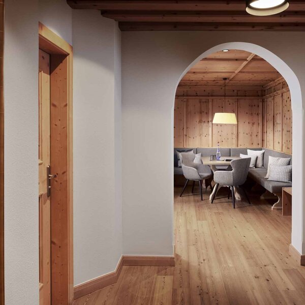 Ein einladender Eingangsbereich mit Holzverkleidung und einem gemütlichen Sitzbereich im Hintergrund, beleuchtet von einer Lampe.