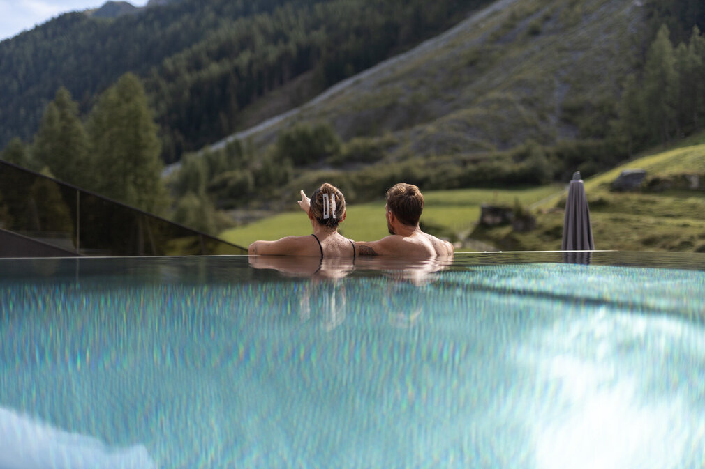 Ein Mann und eine Frau entspannen gemeinsam im Pool und genießen die Aussicht.