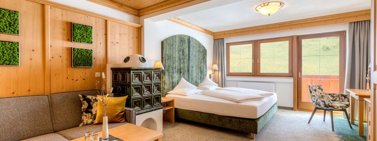 Ein gemütliches Zimmer mit Holzverkleidung, einem großen Bett und einer Sitzecke, die zum Entspannen einlädt.