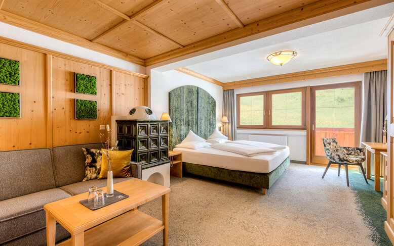 Ein gemütliches Zimmer mit Holzverkleidung, einem großen Bett und einer Sitzecke, die zum Entspannen einlädt.