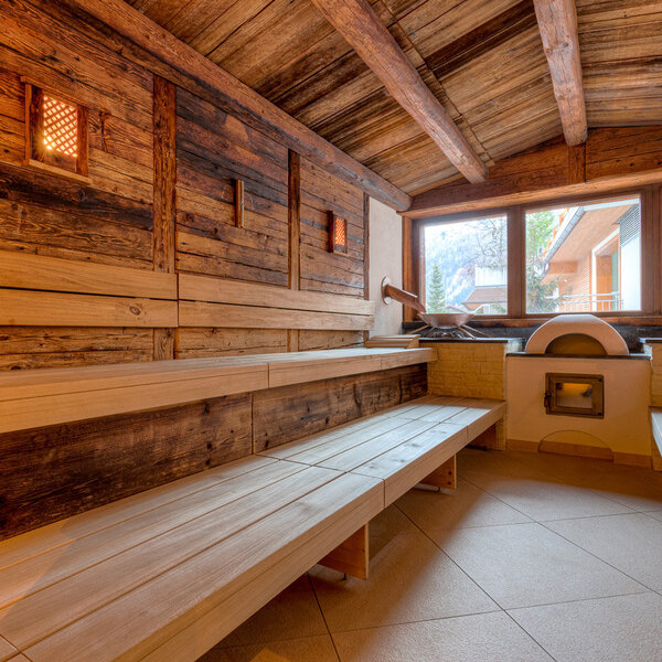 Eine gemütliche Sauna mit Holzverkleidung, großen Fenstern und Blick auf die Berge, die Entspannung und Ruhe ausstrahlt.