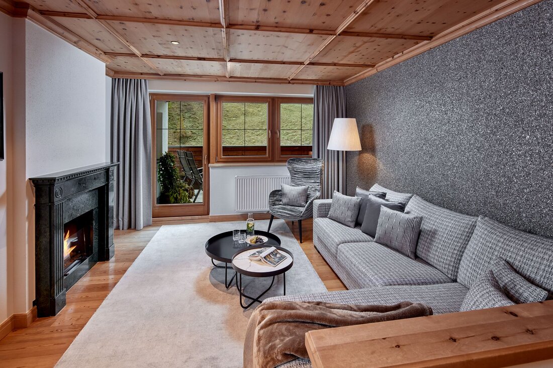Ein stilvolles Wohnzimmer mit einem gemütlichen Sofa, einem modernen Sessel und einem eleganten Kamin, der Wärme ausstrahlt.