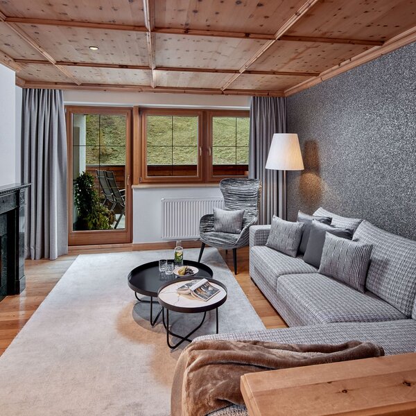 Ein stilvolles Wohnzimmer mit einem gemütlichen Sofa, einem modernen Sessel und einem eleganten Kamin, der Wärme ausstrahlt.