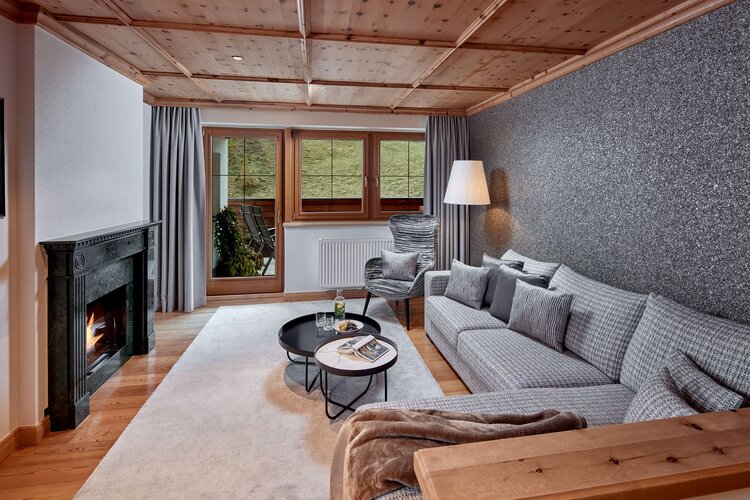 Ein stilvolles Wohnzimmer mit einem gemütlichen Sofa, einem modernen Sessel und einem eleganten Kamin, der Wärme ausstrahlt.