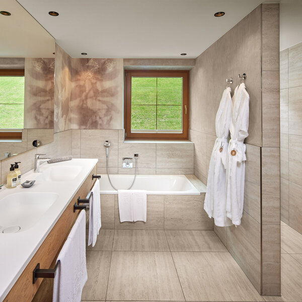 Ein modernes Badezimmer mit einer eleganten Badewanne und einem großen Spiegel, der die stilvolle Einrichtung reflektiert.