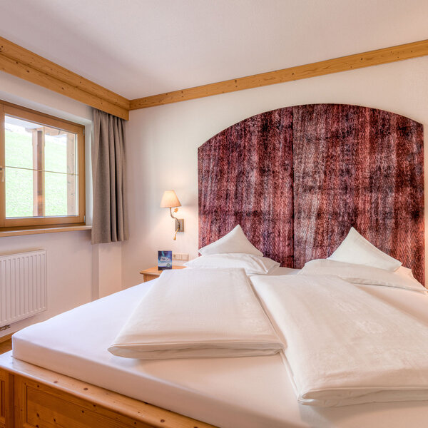 Ein gemütliches Schlafzimmer mit einem großen Doppelbett, das mit weißen Kissen und Decken ausgestattet ist.