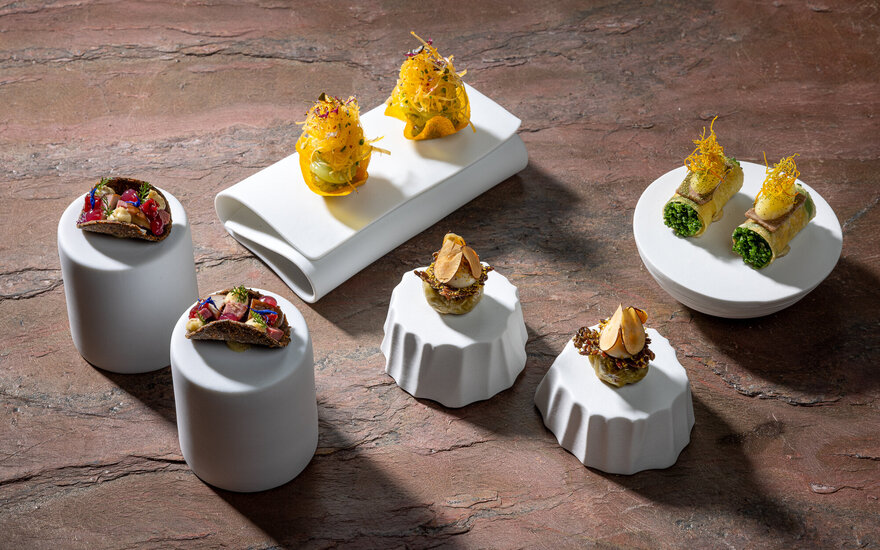 Elegante Häppchen mit verschiedenen Zutaten, kunstvoll auf weißen Tellern angerichtet, die eine moderne kulinarische Präsentation zeigen.