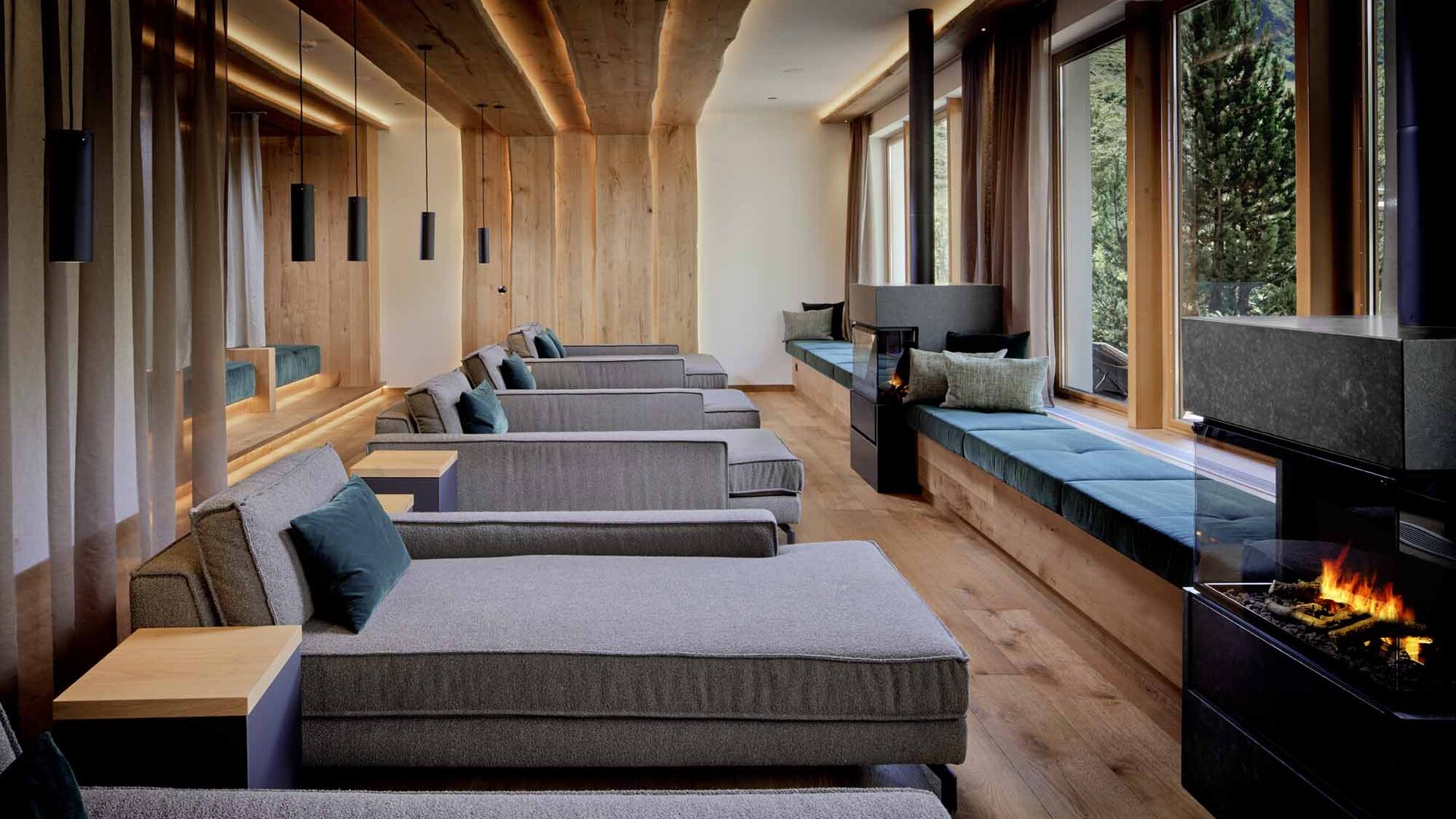 Ein eleganter Ruheraum mit modernen Liegen, sanfter Beleuchtung und großen Fenstern, die auf eine grüne Landschaft blicken.