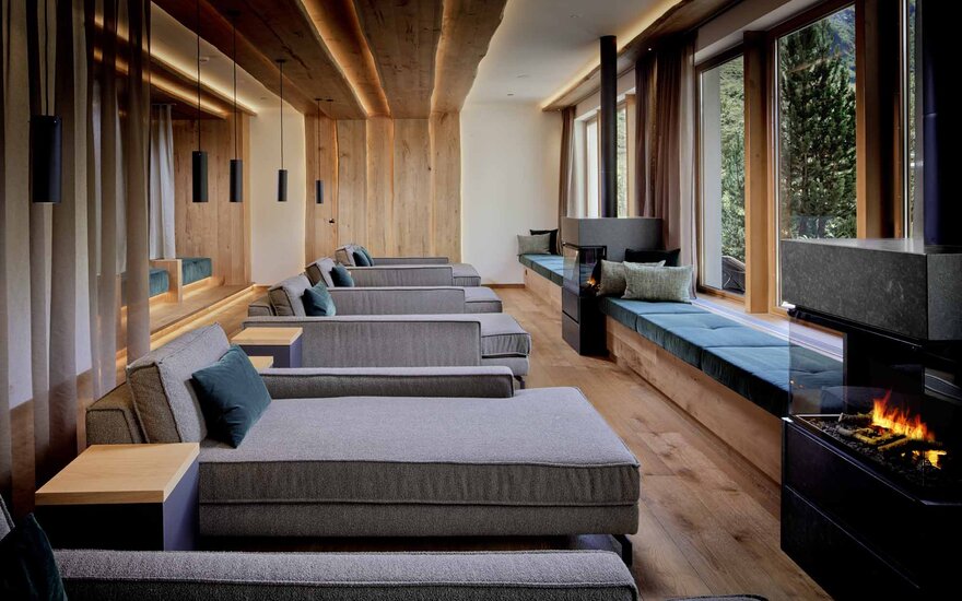 Ein eleganter Ruheraum mit modernen Liegen, sanfter Beleuchtung und großen Fenstern, die auf eine grüne Landschaft blicken.