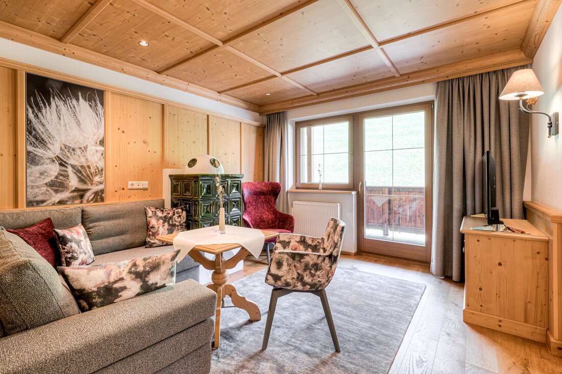 Ein gemütliches Wohnzimmer mit Holzverkleidung, einem großen Fenster und einem eleganten roten Sessel, der einladend wirkt.