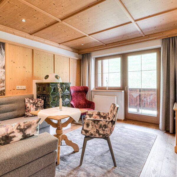 Ein gemütliches Wohnzimmer mit Holzverkleidung, einem großen Fenster und einem eleganten roten Sessel, der einladend wirkt.