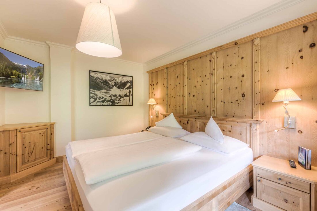 Ein gemütliches Schlafzimmer mit einem großen Doppelbett, Holzvertäfelung und sanfter Beleuchtung für eine entspannende Atmosphäre.