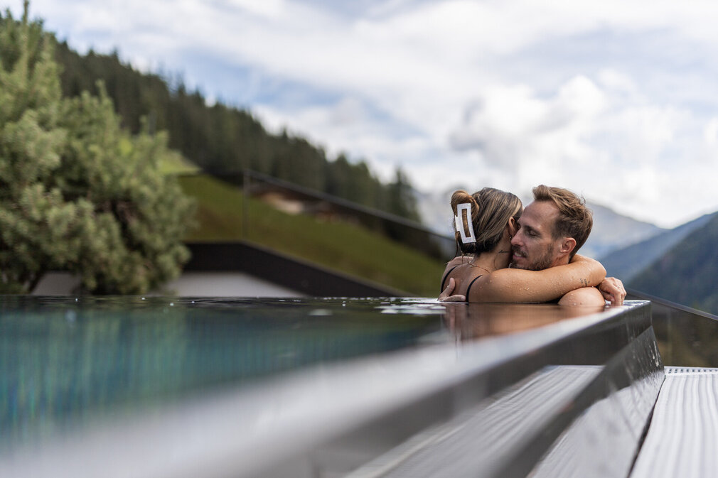 Ein Mann und eine Frau stehen eng umschlungen im Pool.