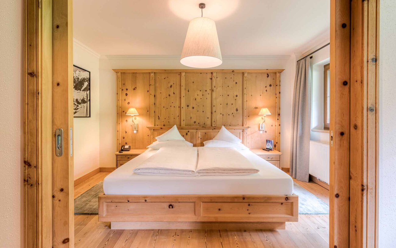 Ein gemütliches Schlafzimmer mit einem großen Doppelbett, Holzvertäfelung und sanfter Beleuchtung, die eine entspannende Atmosphäre schafft.