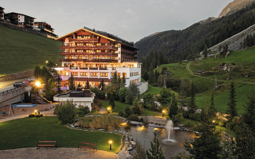 In der Dämmerung erstrahlt das Hotel in warmen Farben, während die umliegende Natur eine ruhige Atmosphäre schafft.