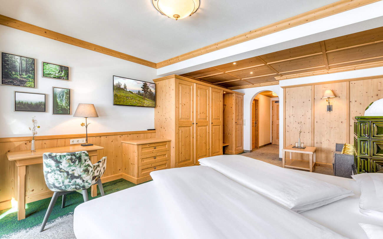 Ein gemütliches Zimmer mit Holzverkleidung, einem großen Bett und einem Schreibtisch, der von einer Lampe beleuchtet wird.
