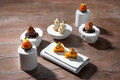Elegante Desserts auf weißen Tellern, darunter ein schokoladiges Gebäck und fruchtige Törtchen, umgeben von Kaffeebohnen.