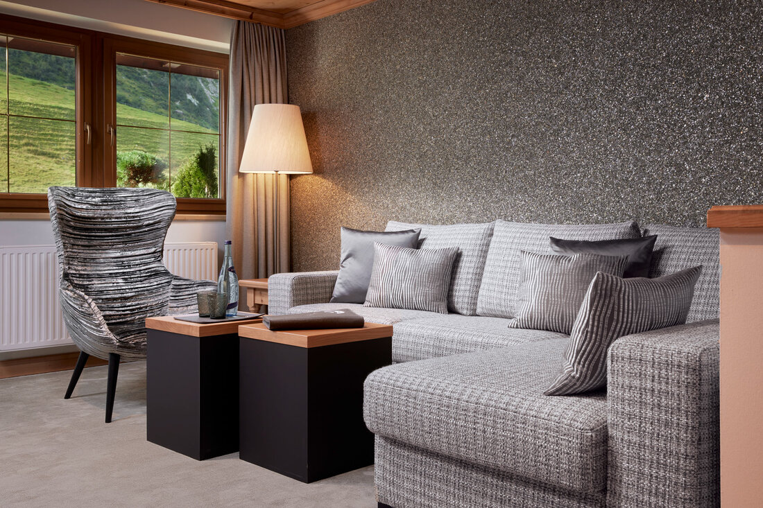 Ein stilvolles Wohnzimmer mit einem grauen Sofa, eleganten Kissen und einem modernen Sessel, der zum Entspannen einlädt.