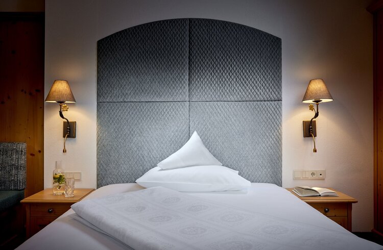 Ein stilvolles Schlafzimmer mit einem gepolsterten Kopfteil und einem Kissen, das auf dem Bett liegt, sorgt für eine einladende Atmosphäre.