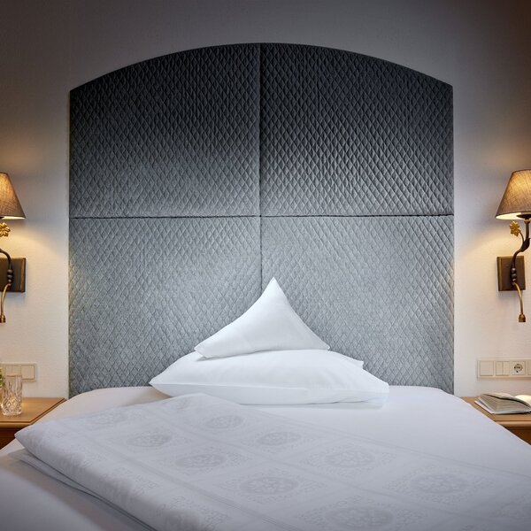 Ein stilvolles Schlafzimmer mit einem gepolsterten Kopfteil und einem Kissen, das auf dem Bett liegt, sorgt für eine einladende Atmosphäre.