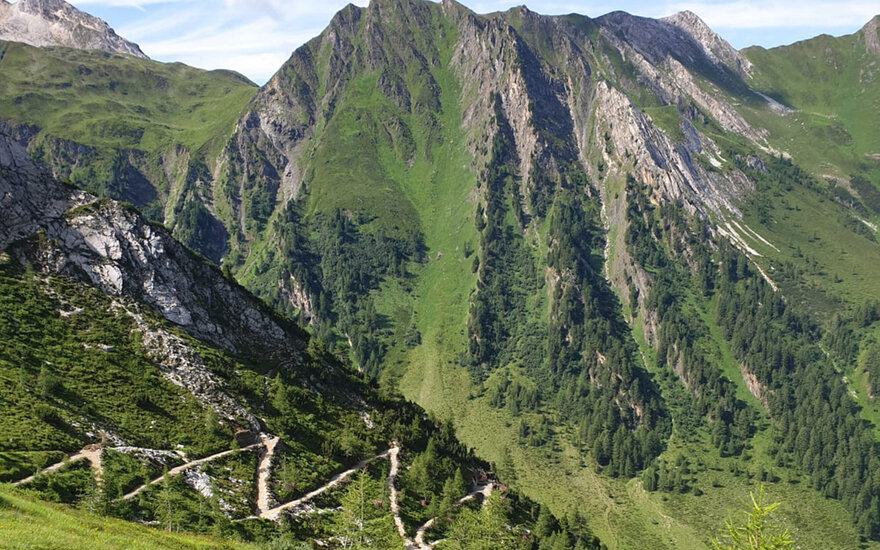 Eine beeindruckende Berglandschaft mit steilen, grünen Hängen und schroffen Felsen, die in den Himmel ragen.