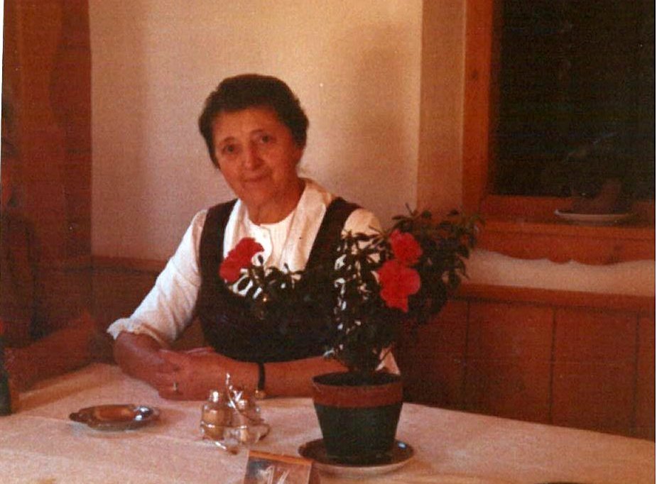 Dame im Dirndl sitzt an Tisch mit Blumentopf