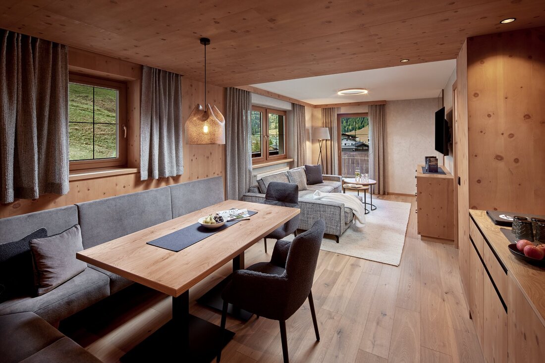 Ein gemütlicher Wohnraum mit Holzverkleidung, einem großen Tisch und einer modernen Couch, die zum Entspannen einlädt.