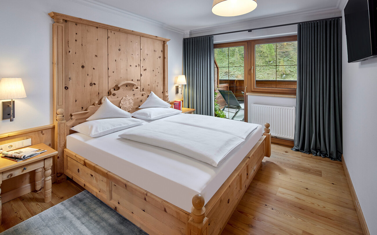 Ein gemütliches Schlafzimmer mit einem großen Holzbett, weißen Kissen und einer warmen Holzverkleidung an der Wand.