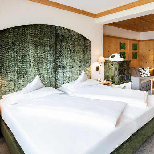 Ein stilvolles Schlafzimmer mit einem großen, grünen Kopfteil und einem gemütlichen Sitzbereich, der einladend wirkt.