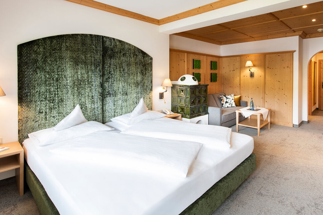 Ein stilvolles Schlafzimmer mit einem großen, grünen Kopfteil und einem gemütlichen Sitzbereich, der einladend wirkt.