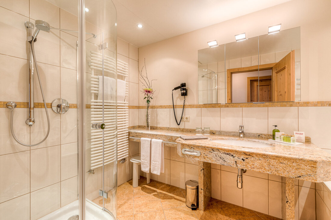 Ein modernes Badezimmer mit einer eleganten Dusche, einem Granitwaschtisch und stilvollen Accessoires, die eine entspannende Atmosphäre schaffen.