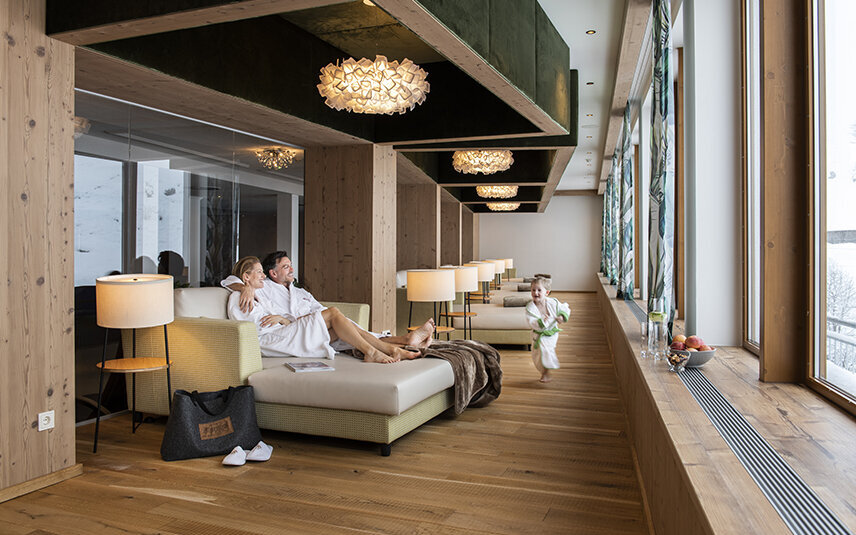 Ein Paar in Bademänteln entspannt, während ein kleiner Junge lachend herumläuft