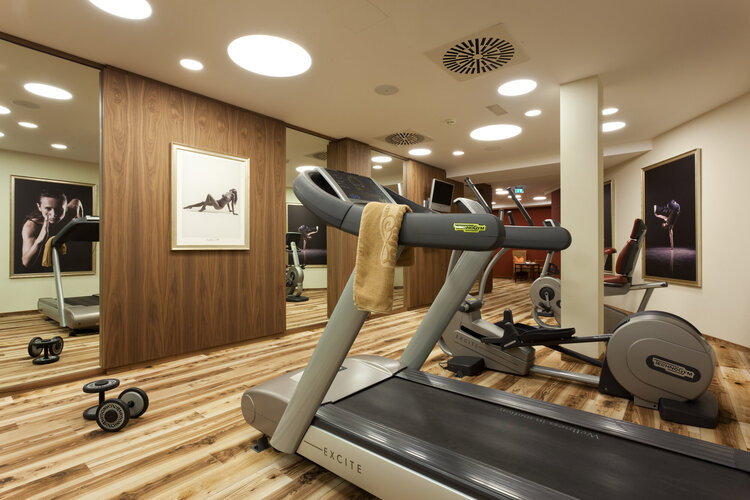 Ein moderner Fitnessraum mit einem Laufband, Gewichten und stilvollen Wandbildern, die eine sportliche Atmosphäre schaffen.